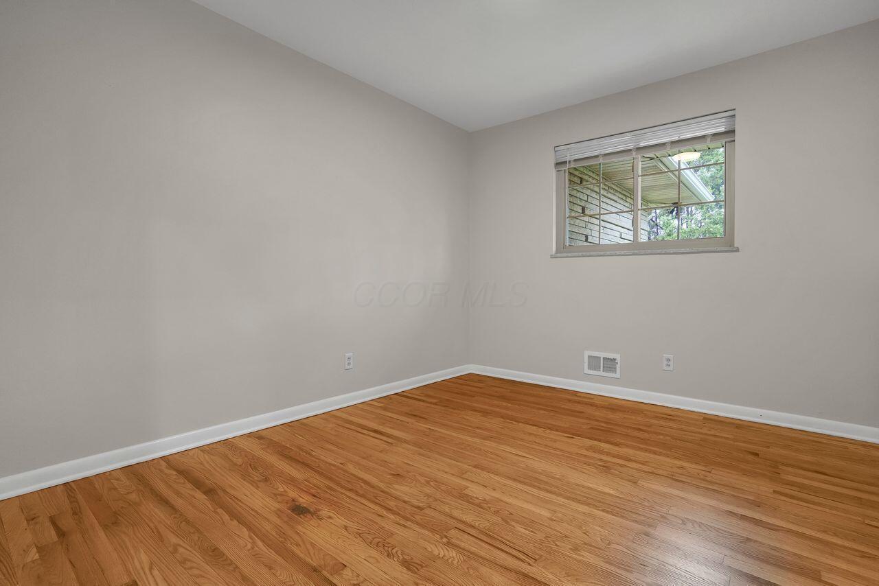 1535 Kenwick Road Columbus, OH 43209 - Photo 11 of 26 Bedroom with hardwood floors, neutral walls, and window overlooking the yard.