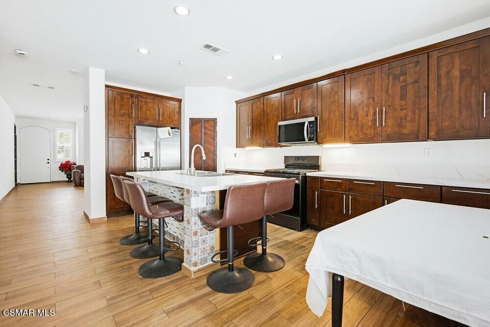1909 Taormina Court Riverside, CA 92507 - Photo 10 of 58 a kitchen with a table chairs a sink dishwasher stove and cabinets with wooden floor