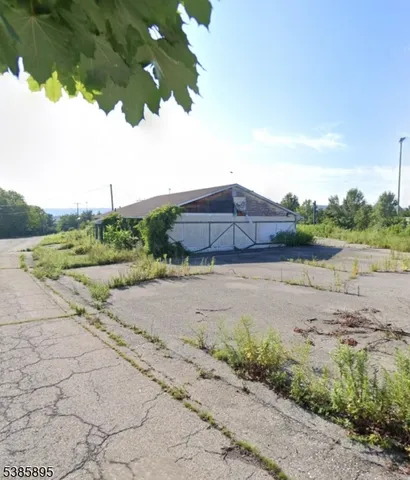 a view of a street with a small yard and large trees