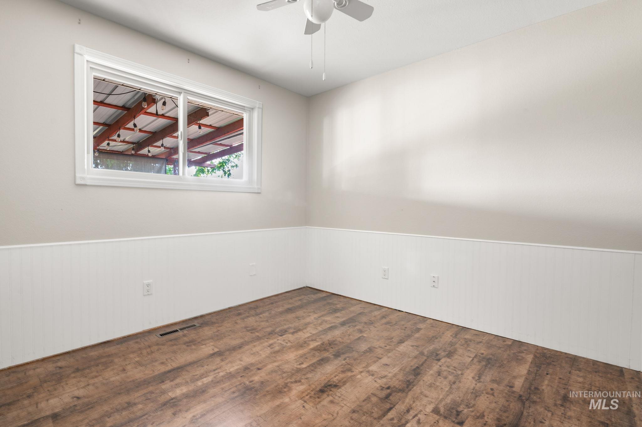 2351 Reservoir Road Clarkston, WA 99403 - Photo 11 of 24 Empty room featuring wood finished floors, wainscoting, and ceiling fan