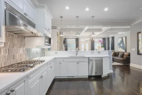 a large white kitchen with lots of counter space a sink and stainless steel appliances