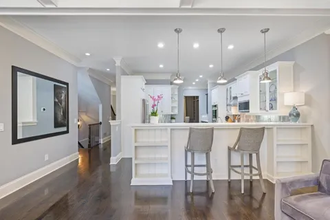 a kitchen with stainless steel appliances kitchen island granite countertop a refrigerator a stove and white cabinets with wooden floor