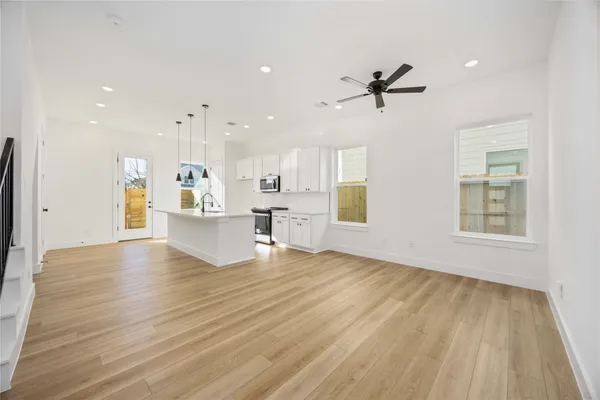 a view of an empty room with a window and wooden floor