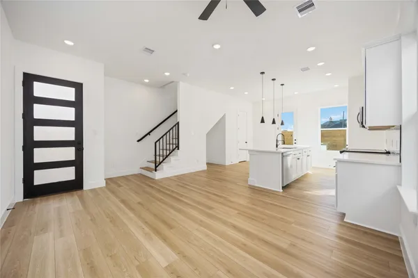 a room with kitchen island stainless steel appliances wooden floor and window