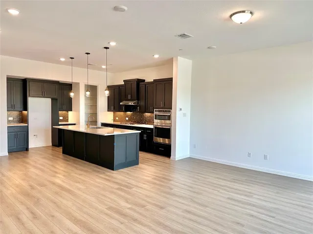 a large kitchen with stainless steel appliances kitchen island granite countertop a large counter top and view of living room