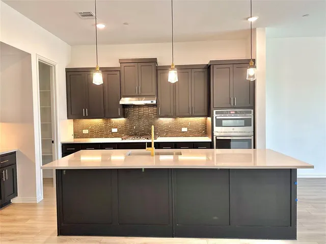 a kitchen with kitchen island stainless steel appliances a sink and wooden floor