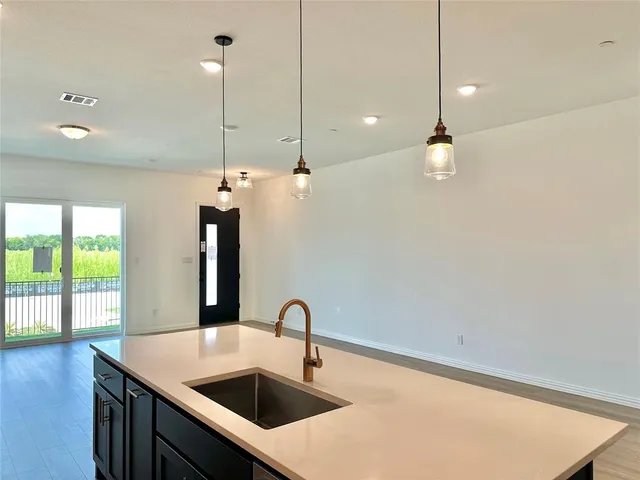 a kitchen with a sink a chandelier and wooden floor