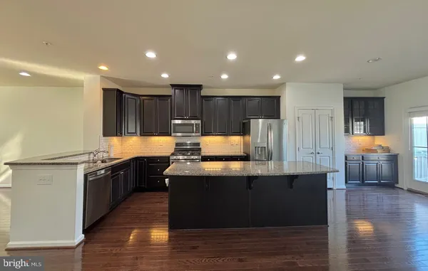 a kitchen with kitchen island granite countertop a sink and a stove top oven