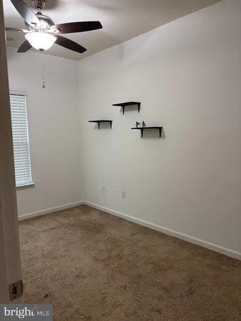 an empty room with a window and a ceiling fan