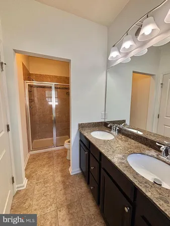 a bathroom with a granite countertop sink a mirror and a shower