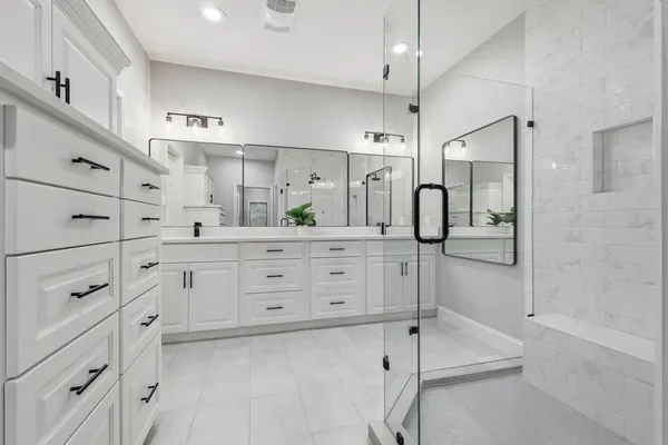 a bathroom with a double vanity sink a mirror a glass door and shower