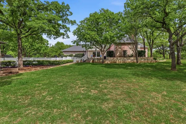 a view of a house with a big yard and large trees