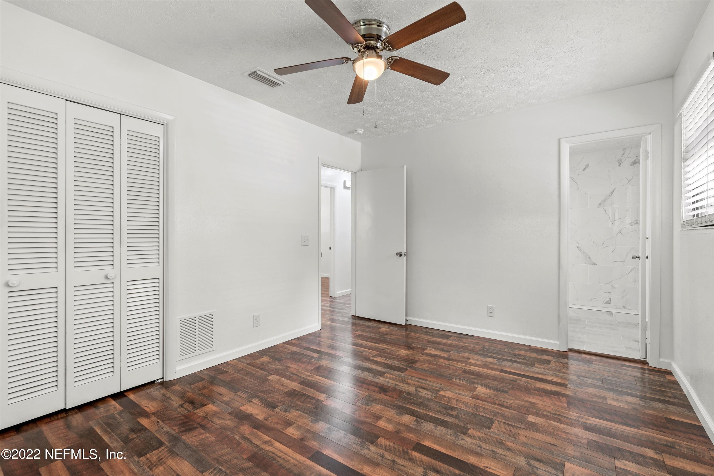 5092 Harvey Grant Road Fleming Island, FL 32003 - Photo 22 of 38 an empty room with wooden floor ceiling fan and windows