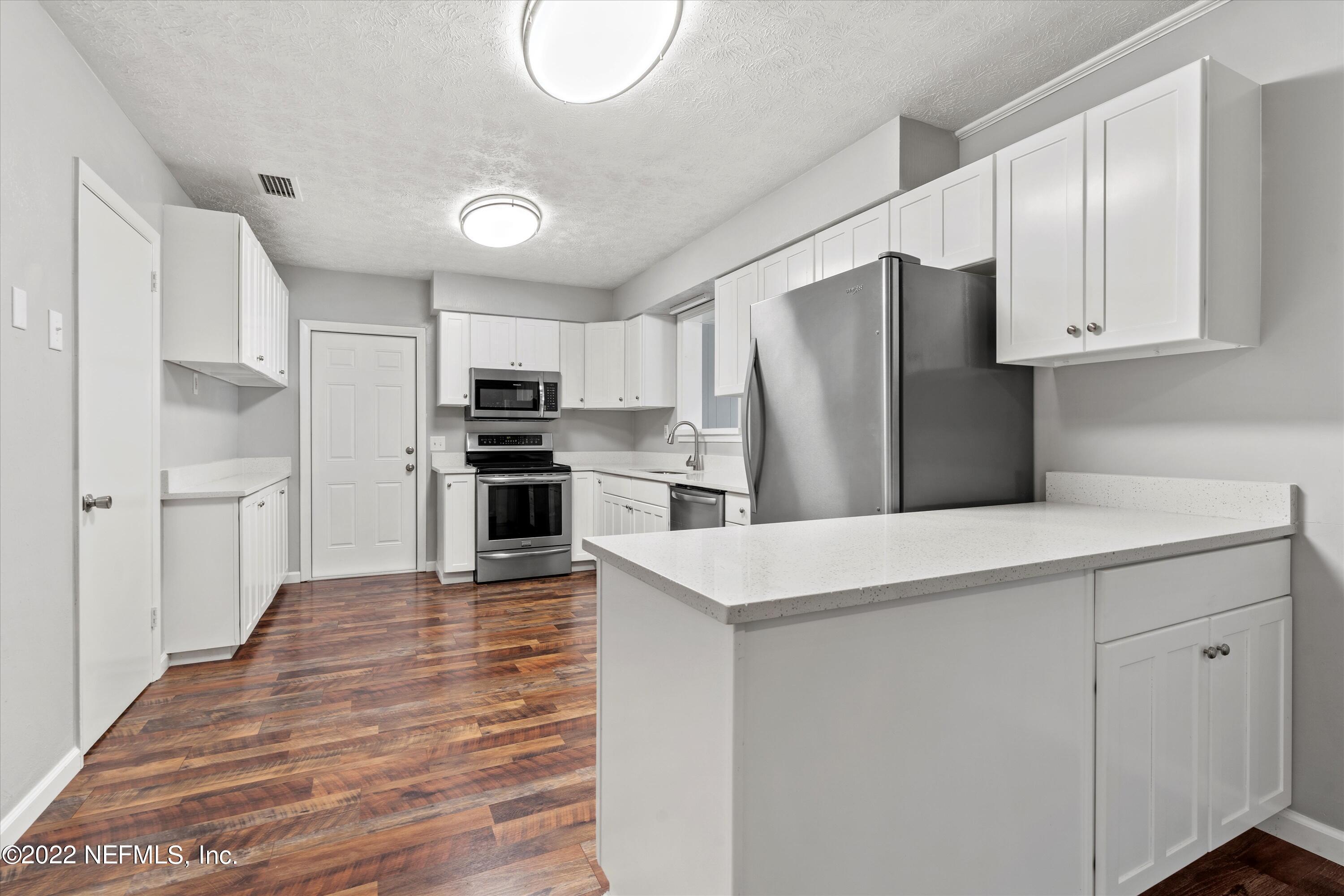 5092 Harvey Grant Road Fleming Island, FL 32003 - Photo 10 of 38 a kitchen with wooden cabinets and stainless steel appliances