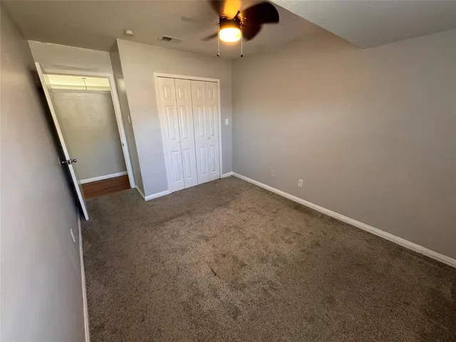 an empty room with ceiling fan and window