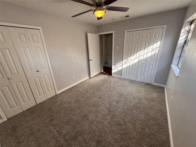 a view of an empty room with window and hardwood floor