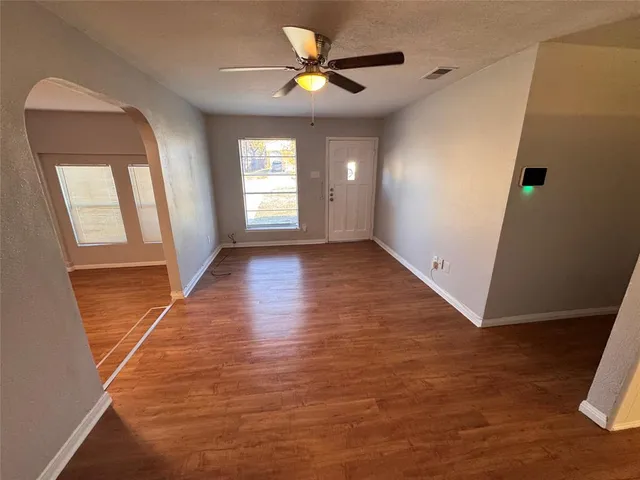 a view of an empty room with window and wooden floor