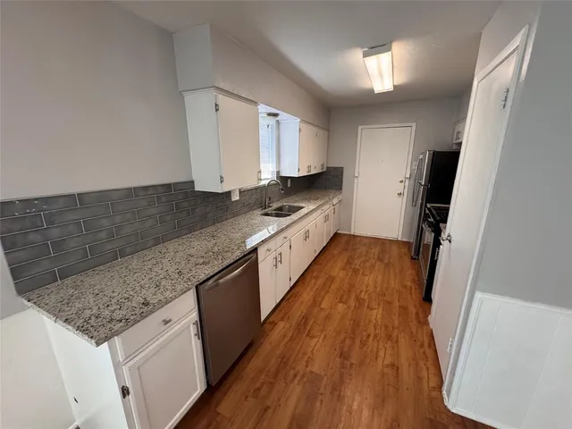 a kitchen with granite countertop a sink and wooden floor