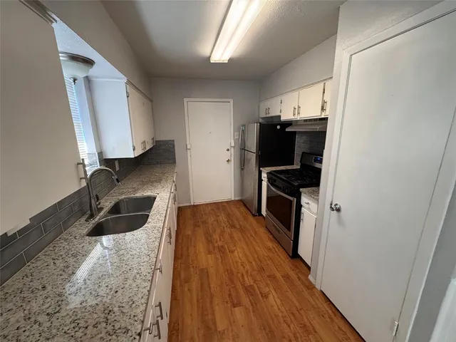 a kitchen with granite countertop a refrigerator and a sink