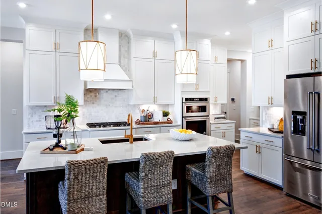 a kitchen with stainless steel appliances granite countertop a sink a stove a refrigerator and a dining table with wooden floor