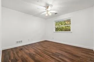 an empty room with wooden floor and ceiling fan