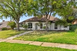 a front view of a house with a garden and trees