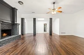 a view of an empty room with wooden floor fireplace and a window