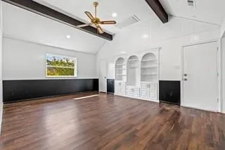 a view of an empty room with a window and wooden floor