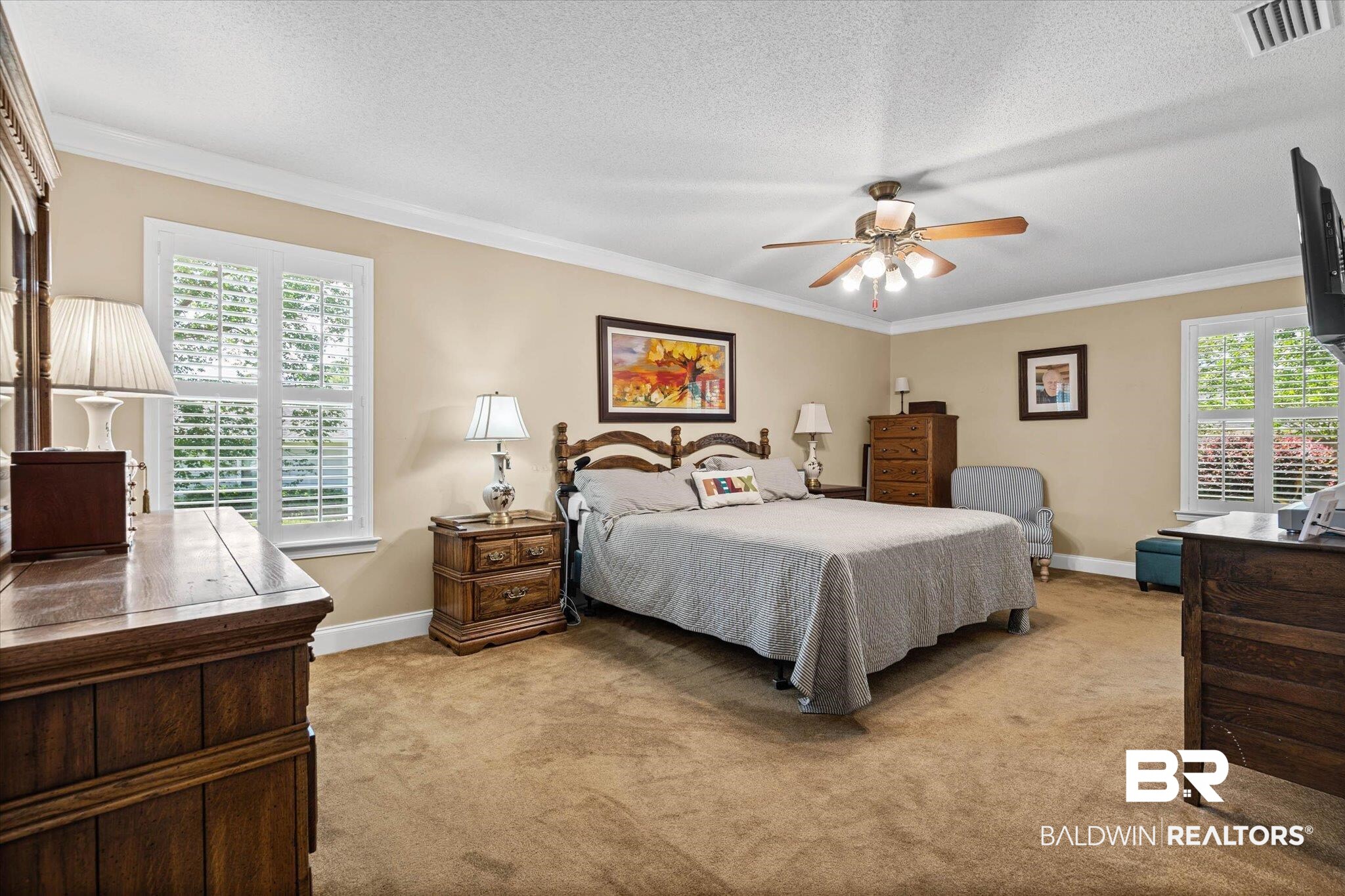 7410 Smithfield Road East Mobile, AL 36695 - Photo 11 of 24 Carpeted interior room featuring crown molding, two windows with plantation shutters, a ceiling fan with integrated lighting, and neutral wall tones