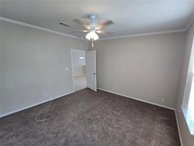 an empty room with a chandelier fan and closet
