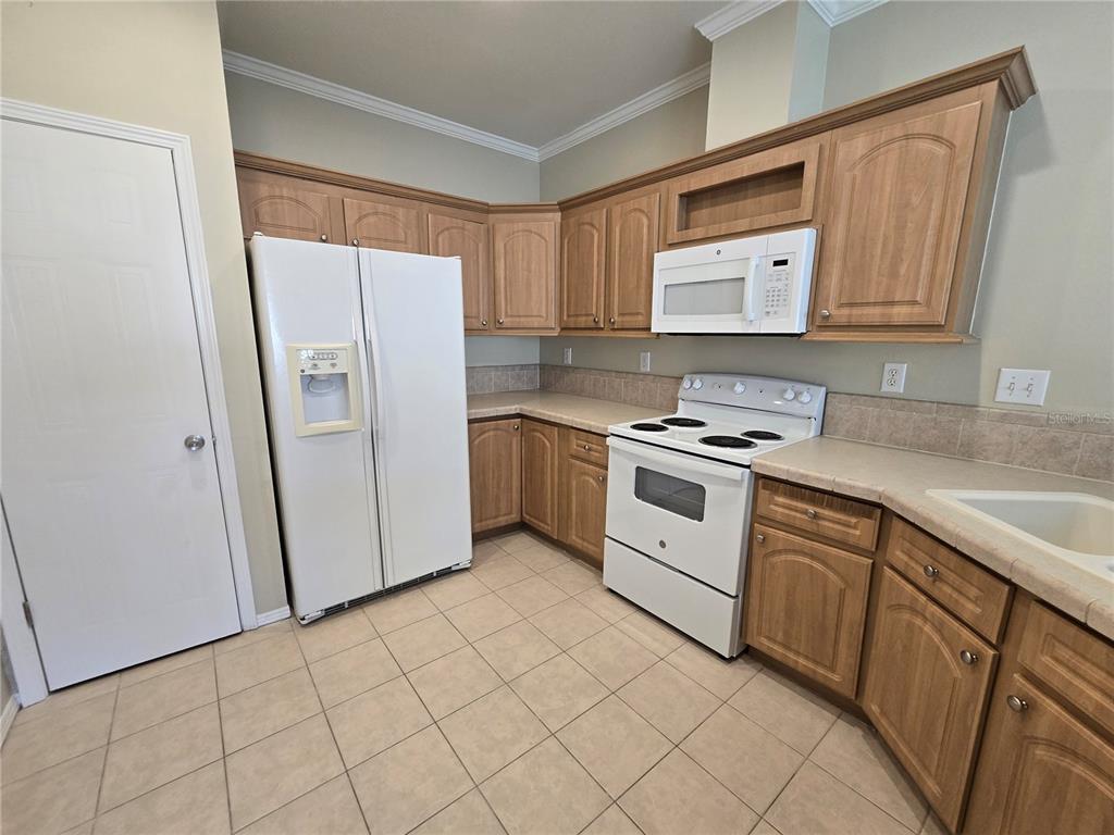 7644 Sailwinds Pass Port Richey, FL 34668 - Photo 9 of 22 a kitchen with white cabinets and white appliances