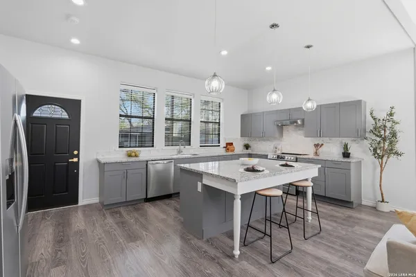 a kitchen with a sink a refrigerator a stove a dining table and chairs