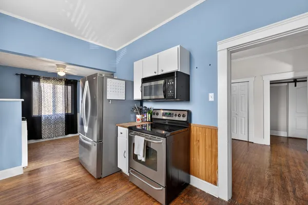a kitchen with stainless steel appliances a stove a microwave a sink a refrigerator and wooden floor