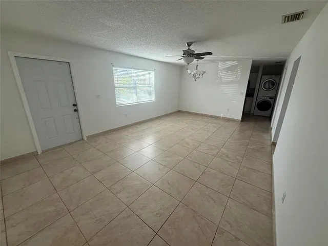 an empty room with a ceiling fan and window