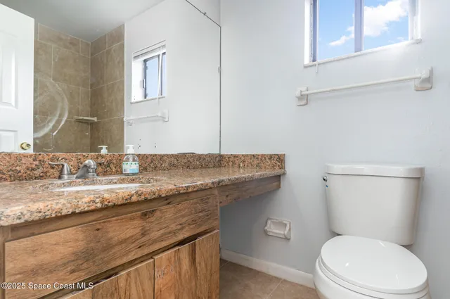 a bathroom with a granite countertop toilet sink and mirror