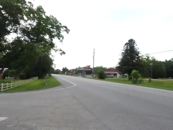a view of a road with a big yard and large trees