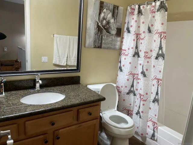 a bathroom with a granite countertop toilet sink and mirror