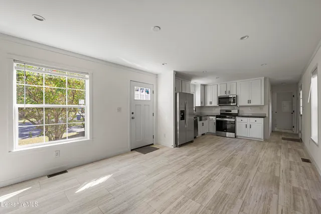 a large kitchen with stainless steel appliances granite countertop a stove a sink dishwasher a refrigerator with wooden floor and cabinets