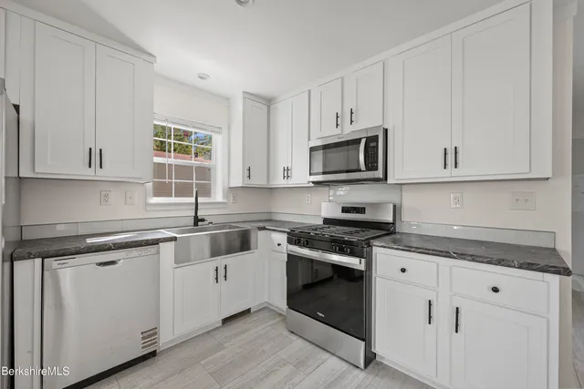 a kitchen with cabinets stainless steel appliances a sink and a window