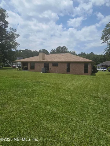 a view of a house with a big yard and large trees