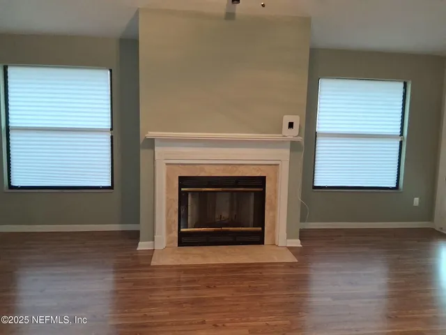 a view of an empty room with wooden floor and a fireplace