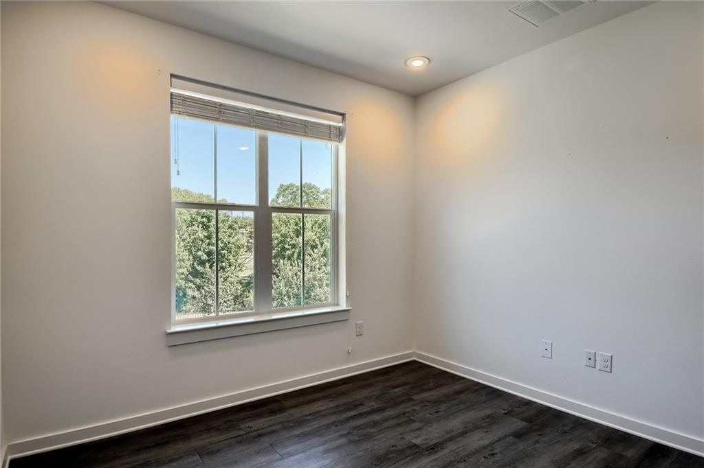 2624 Metcalfe Road, Unit 7 Austin, TX 78741 - Photo 21 of 31 Room featuring a large window with white trim, wood-finish flooring, recessed lighting, and white baseboards