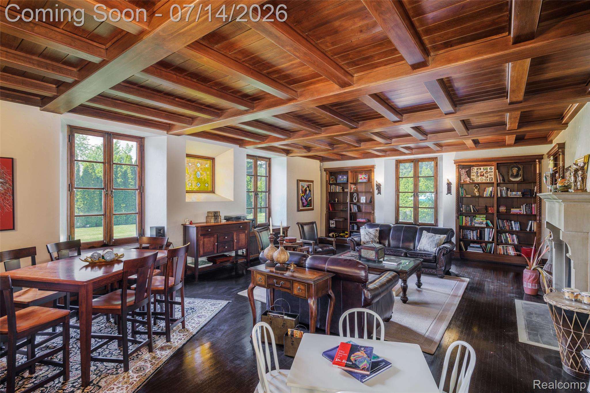 189 Cloverly Road Grosse Pointe, MI 48236 - Photo 17 of 96 Exposed wood beam ceiling with recessed panels, dark wood-finish flooring, multiple casement windows with dark wood frames, built-in shelving, and a prominent fireplace with a stone mantel