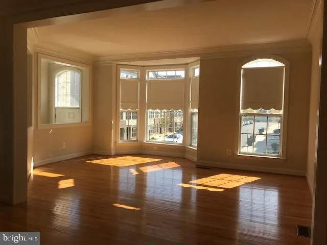 a view of empty room with floor to ceiling window and wooden floor