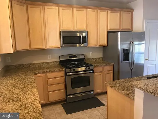 a kitchen with stainless steel appliances granite countertop a stove a refrigerator and a microwave