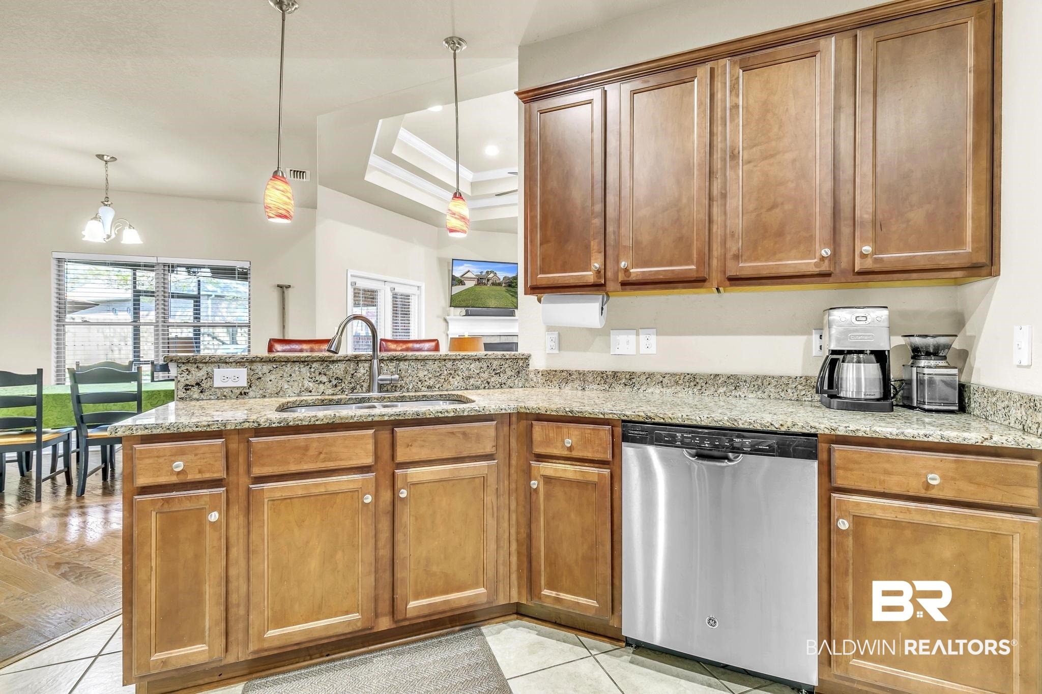 21439 Brick Stack Lane Fairhope, AL 36532 - Photo 15 of 32 Kitchen with a sink, light stone countertops, a peninsula, stainless steel dishwasher, and brown cabinetry