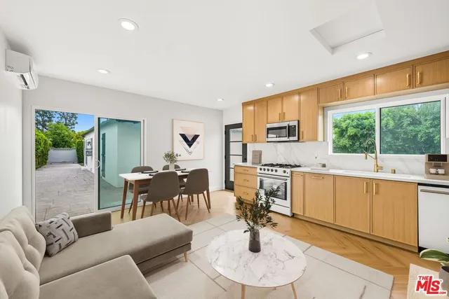 a living room with furniture a large window with kitchen view and a sink