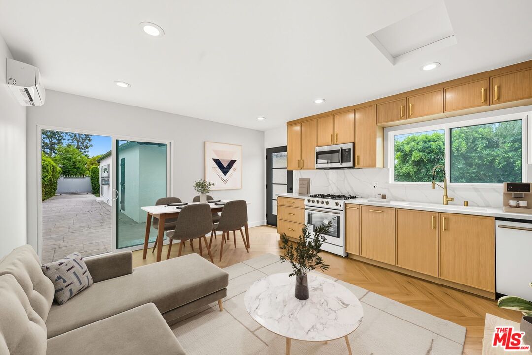 a living room with furniture a large window with kitchen view and a sink