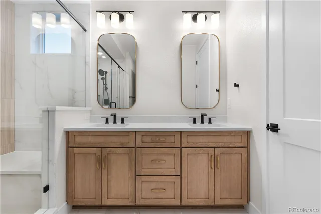 a bathroom with double vanity sinks a mirror and a bathtub