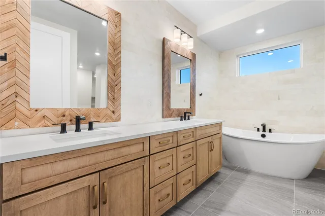 a spacious bathroom with double vanity two mirror a bathtub and
